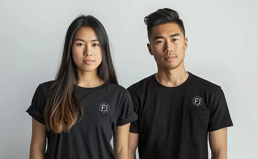 Two people wearing black t-shirts with a Flujo logo on the upper left side. The person on the left is a woman with long dark hair, and the person on the right is a man with short dark hair.