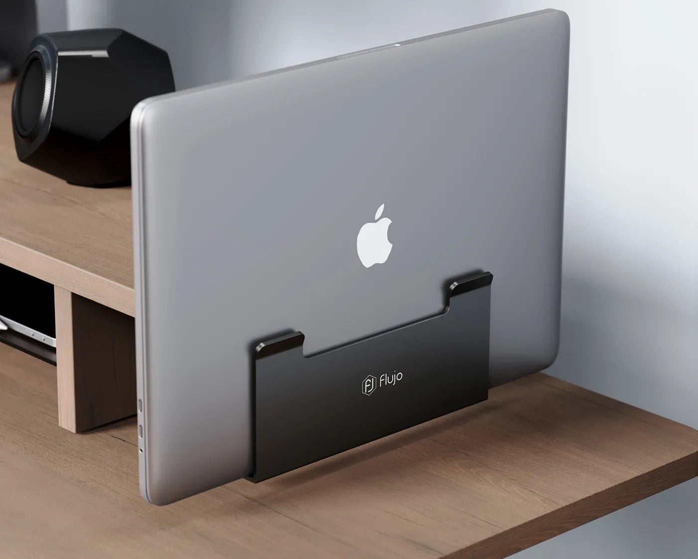 A laptop docked vertically under the monitor riser, demonstrating the riser's modular design and space-saving features.