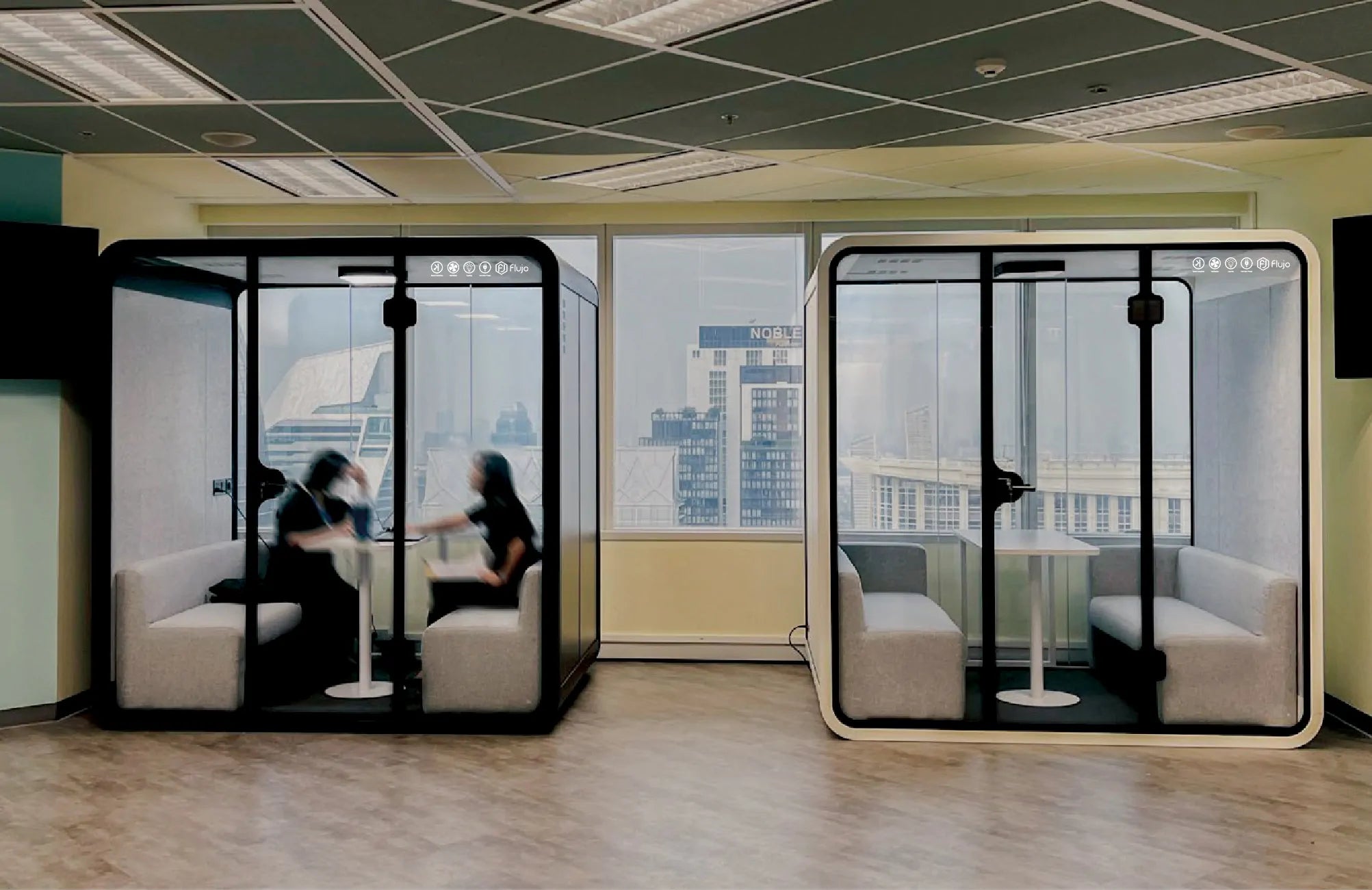 Flujo acoustic office meeting pods in a modern open-plan workspace, two 4-person glass pods with sofa seating for private discussions in Singapore offices