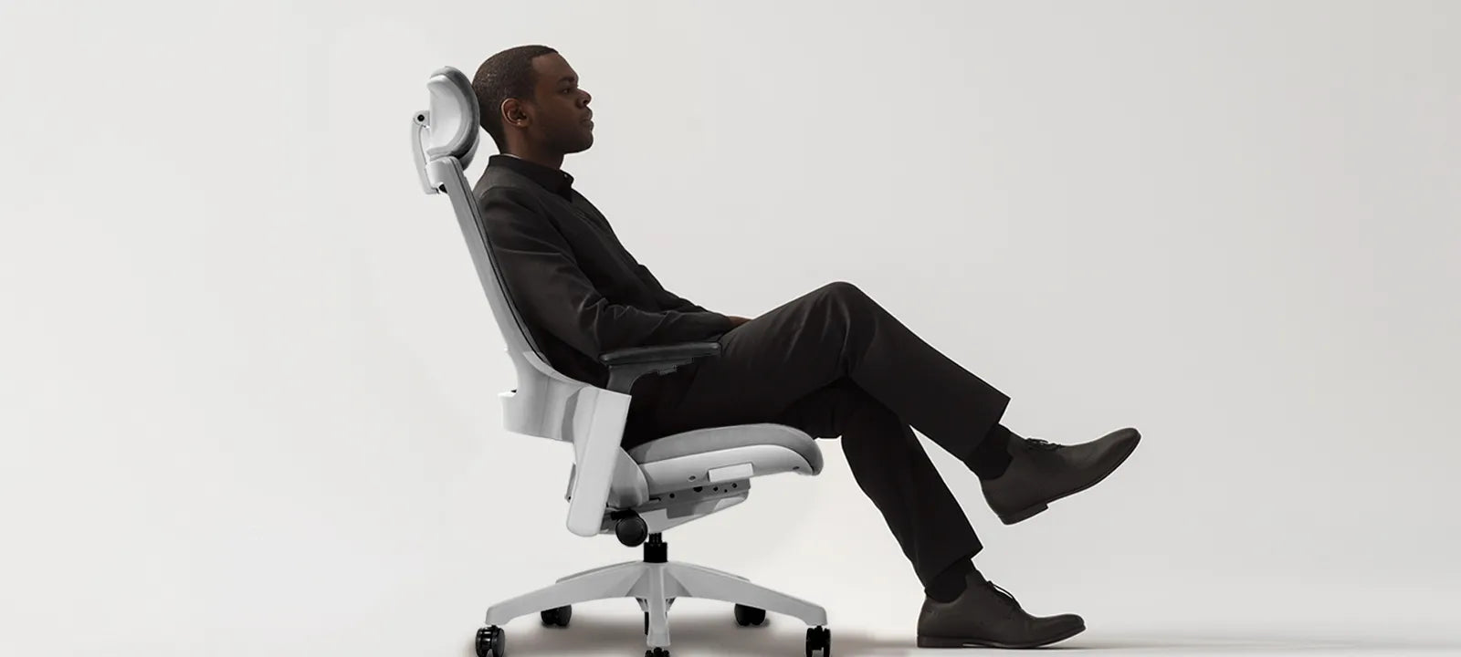 Flujo Angulo Chair showcased with a man seated in comfort, emphasizing the sleek white design and ergonomic back support.