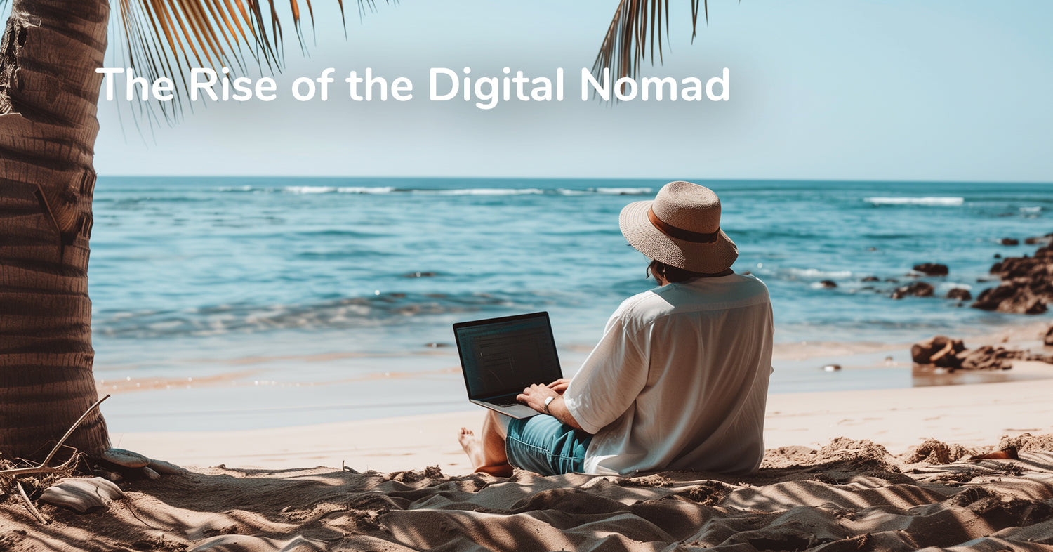 A person sitting on a sandy beach under a palm tree, wearing a wide-brimmed hat, and working on a laptop with the ocean in the background. The text "The Rise of the Digital Nomad" is overlaid at the top of the image.