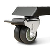 Close-up of a Flujo caster wheel with a sleek design, showcasing the brand logo on the wheel fork and a lockable brake mechanism on a swivel chair or table