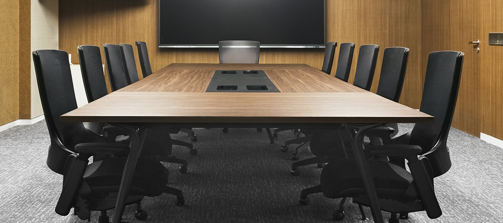 Elegant boardroom with Flujo office chairs around a large wooden table, illustrating a professional and stylish meeting environment.