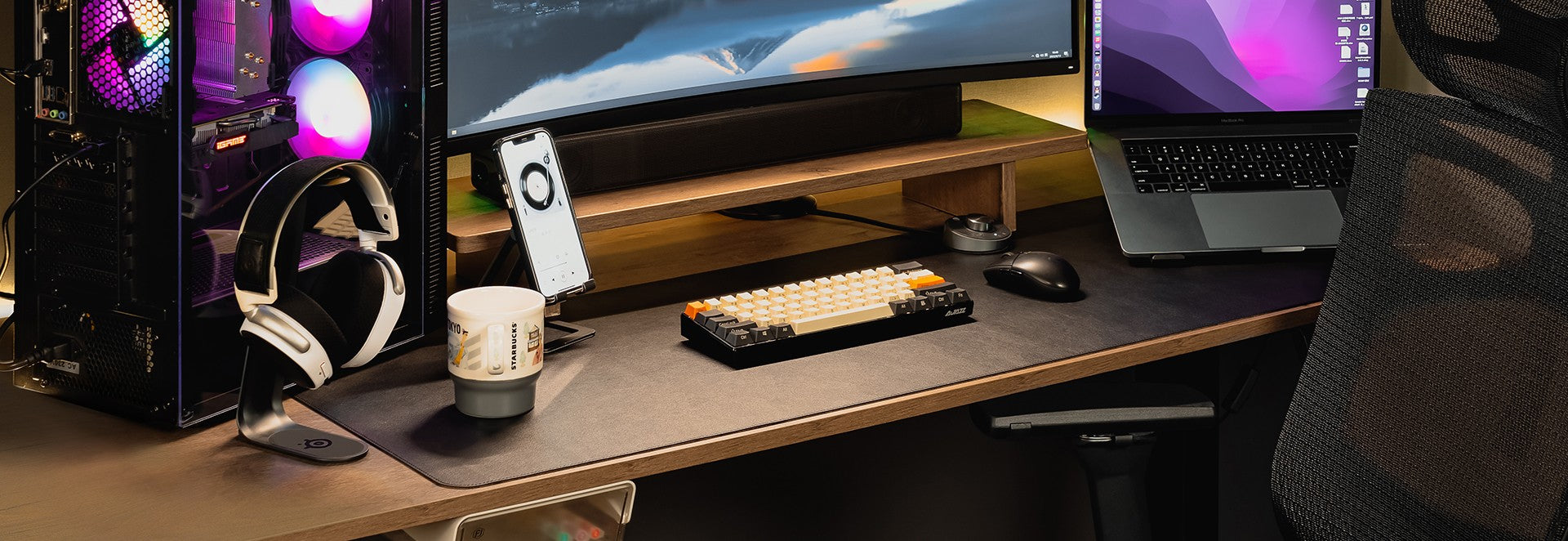 mage showcasing a modern desk setup with Flujo accessories, including a phone stand and keyboard, set against a backdrop of a gaming PC and a monitor.