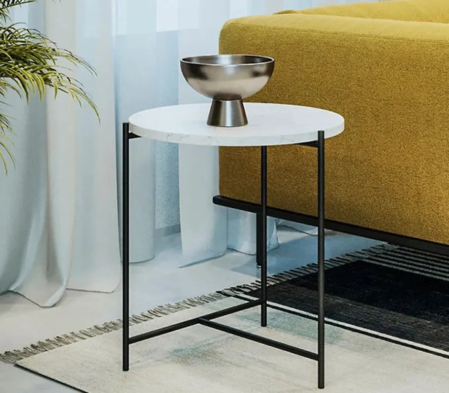Elysia round marble coffee table with minimalist black metal frame, styled in a modern living room beside a yellow fabric sofa