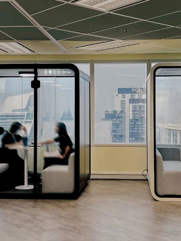 Flujo acoustic office meeting pods in a modern open-plan workspace, two 4-person glass pods with sofa seating for private discussions in Singapore offices