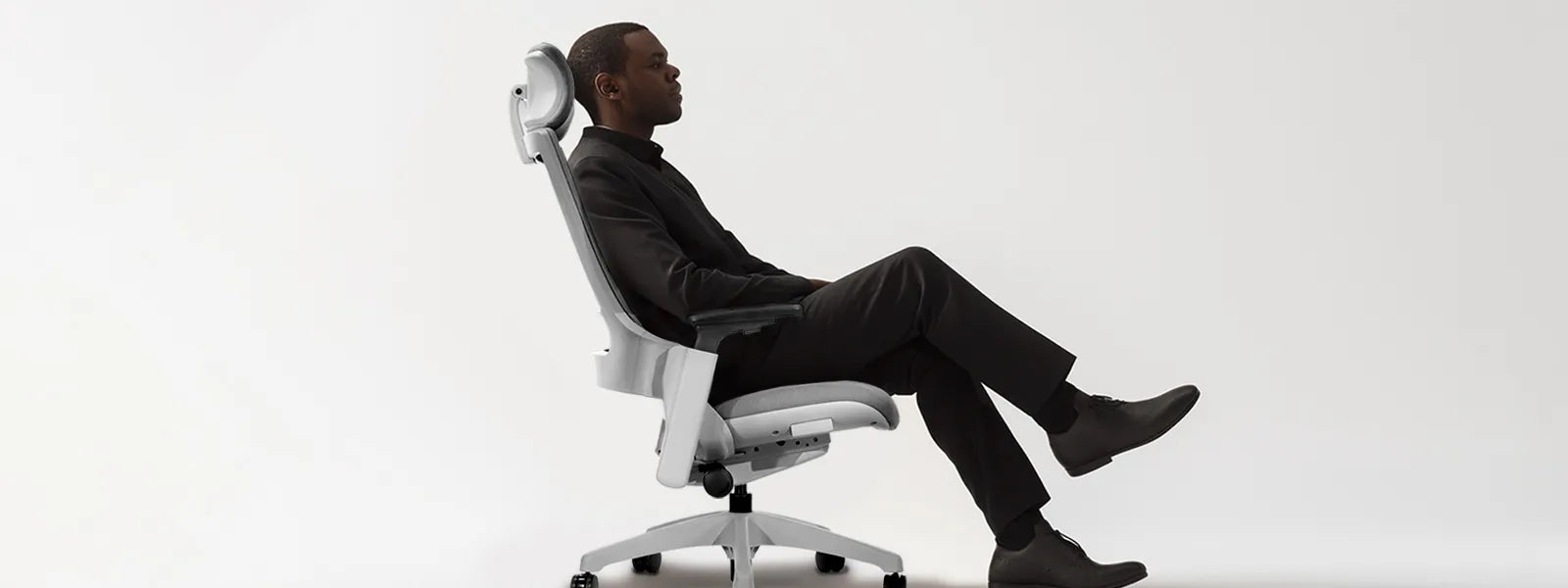 Flujo Angulo Chair showcased with a man seated in comfort, emphasizing the sleek white design and ergonomic back support.