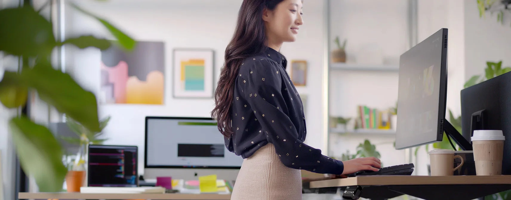 Professional woman using a standing desk in a vibrant office environment
