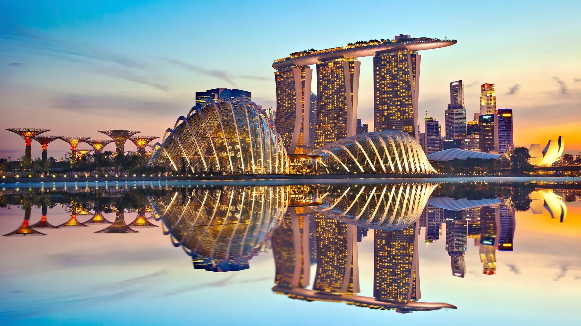 Iconic Singapore skyline at dusk with Marina Bay Sands and the Gardens by the Bay, reflecting the city's modernity and beauty.