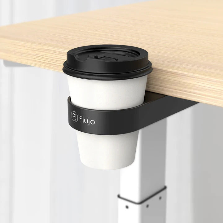 Disposable coffee cup held in a Flujo branded clip-on desk cup holder attached to a wooden table, providing a smart space-saving solution.